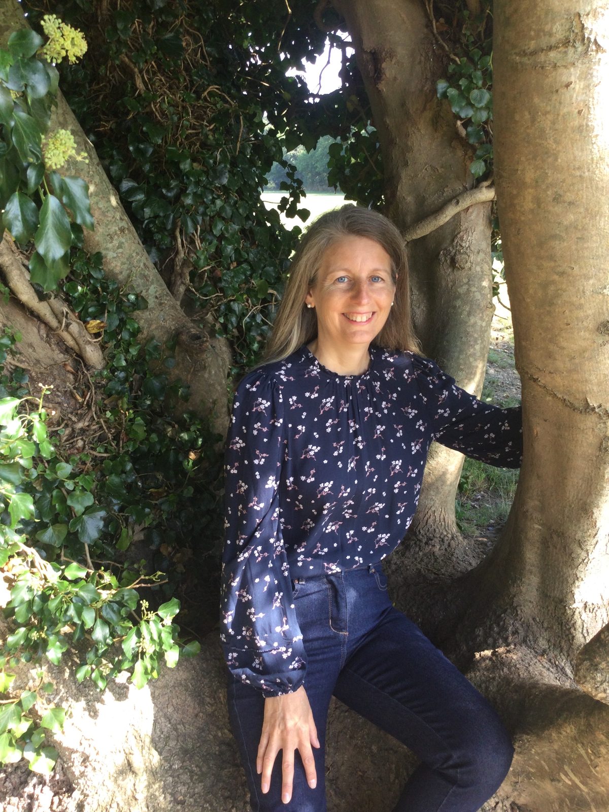 Catherine Buchan smiling, sitting beneath a tree